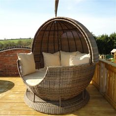 a wicker swing chair with cushions on a deck