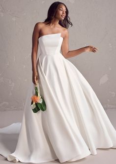 a woman in a white wedding dress with flowers on the side and her hand out