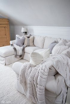 a white couch with pillows and blankets on it in a room that has an attic