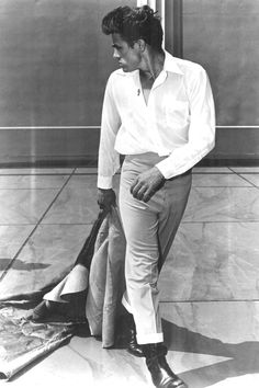 an old photo of a man in white shirt and pants sitting on the floor with his umbrella