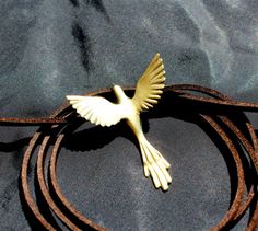 a white bird is sitting on top of a brown leather cord with a black background