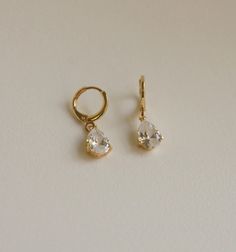 two pairs of earrings on a white surface with one earring in the shape of a heart