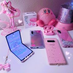 various cell phones are arranged on a table with pink accessories and other items in the background