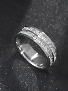 a white gold wedding band with princess cut diamonds set in the center, on a black background