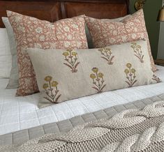 a bed with two pillows on top of it next to a night stand and lamp