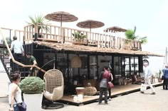 people are standing on the deck of a houseboat with wicker furniture and umbrellas