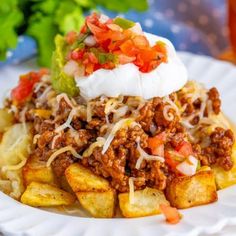 a close up of a plate of food with potatoes and meat on it, garnished with sour cream