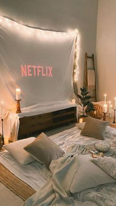 a bed with white sheets and candles on the wall next to it that says netflix