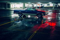 a blue car parked in a parking lot next to a red and white building at night