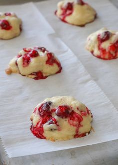 several cookies with cranberry toppings sitting on parchment paper