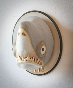 a white wall mounted clock with an animal's head and teeth on the face