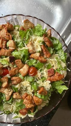 a salad with lettuce, tomatoes and chicken in a bowl on a counter