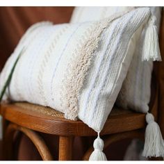 a white pillow sitting on top of a wooden chair next to a potted plant