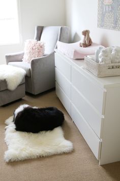 a baby's room with white furniture and sheepskin rugs