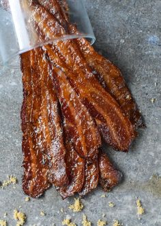 some bacon sticks are in a plastic container on the ground with mustard flakes around them