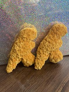 two brown teddy bears sitting next to each other on a wooden floor in front of a glitter wall