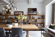 a dining room table surrounded by chairs and bookshelves