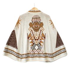 Vintage 70s Aztec Warrior Tribal Ethnic Knit Zip Front Hooded Cape. One Size Fits Most. Medium Weight Acrylic Knit Cape With A Woven In Tribal Aztec Warrior And Symbols Pattern In Shades Of Brown And Old Gold On Ivory. Zips Up The Center Front With A 20" Long Silver Tone Metal Separating Zipper. Excellent Condition Beige Bohemian Winter Cape, Bohemian One Size Cream Poncho, White Bohemian Poncho For Winter, Bohemian White Shawl Cape, White Bohemian One-size Cape, Mayan Clothing, Desert Clothing, Aztec Warrior, Knitted Cape