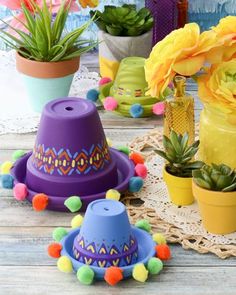 several colorful hats are sitting on a table with flowers in the vases and potted plants