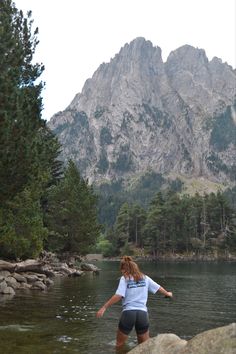 a woman wading in the water near mountains