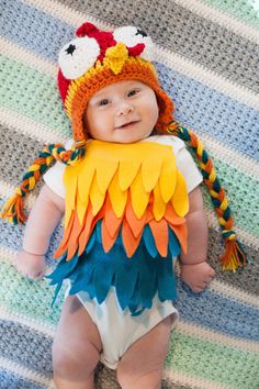 a baby wearing a bird costume on top of a blanket