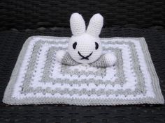 a white crocheted bunny sitting on top of a blanket