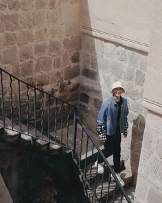 a man standing at the top of a set of stairs next to a stone building