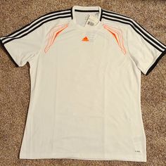 White Adidas Climalite Jersey With Neon Orange Details And Logo Stitching As Well As Black Stripes On The Shoulders And Cuffs. Breathable And Lightweight For The Most Active Sportsman! Sporty White Breathable T-shirt, White Adidas Sporty T-shirt, Adidas White Sporty T-shirt, White Adidas T-shirt For Sports Events, Adidas White T-shirt For Sports Season, Adidas White T-shirt For Sports, White Adidas T-shirt, Adidas White Activewear With Three Stripes, White Short Sleeve Activewear For Sports Events