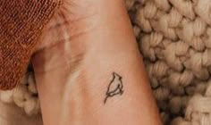 a small tattoo on the wrist of a woman's left arm, with a tiny bird