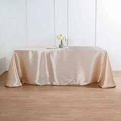 a table with a white flower vase on it and a light pink cloth draped over it