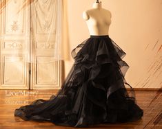 a mannequin wearing a black tiered dress in front of a white wall