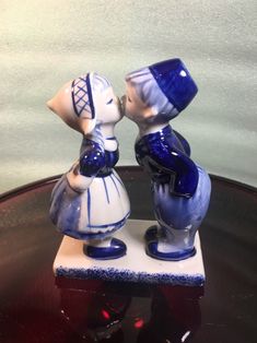 two blue and white figurines sitting on top of a glass table next to each other