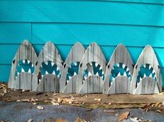 a row of wooden picket boards with blue and white designs on them, sitting in front of a blue house