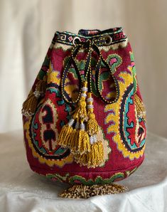 a colorful purse with tassels on it sitting on top of a white cloth