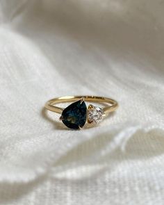 a gold ring with blue and white stones on it, sitting on a white cloth