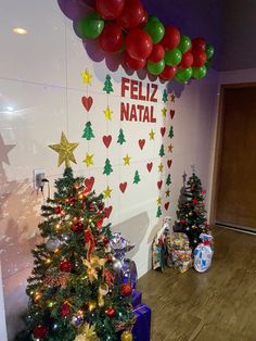 christmas trees and presents in front of a wall with the words feliz natl on it