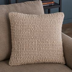 a close up of a pillow on a couch with a book shelf in the background