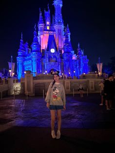 a woman standing in front of a castle at night