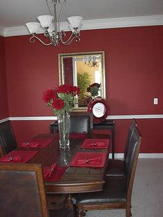 the dining room table is set with red napkins and place settings for four people