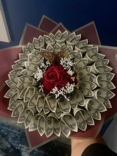 a bouquet made out of dollar bills with a red rose on top and white flowers in the middle