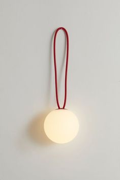 a red string hanging from the side of a wall light with a white ball on it