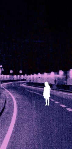 a blurry image of a person standing on the side of a road at night