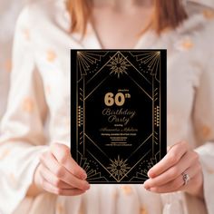 a woman holding up a black and gold 60th birthday card