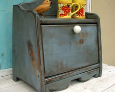 an old wooden cabinet with two baby bottles on top and a bird perched on it