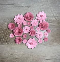 pink paper flowers are arranged on a wooden surface