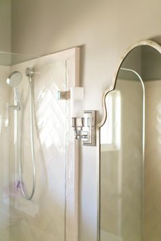 a bathroom with a shower, mirror and toilet paper dispenser on the wall