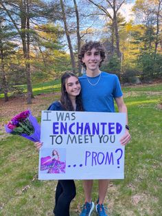 a man and woman standing next to each other holding a sign that says i was enchanted to meet you prom