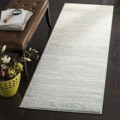 a large white rug on top of a wooden floor next to a bench and chair