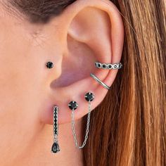 a close up of a person wearing ear piercings with black stones on the side