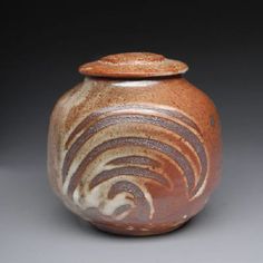 a brown and white vase sitting on top of a table